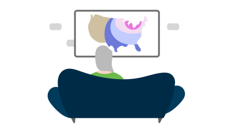 A woman sitting on a couch watching the weather report on tv.